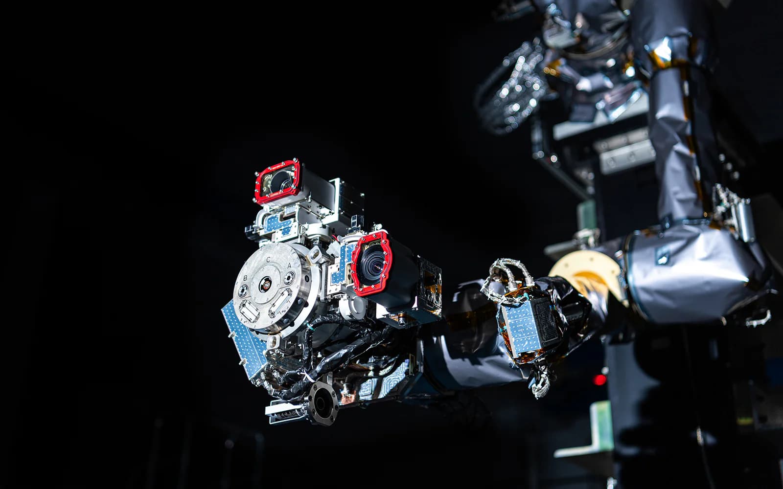 NASA OSAM-1 robotic servicing arm with a detailed circular tool head against a black background.