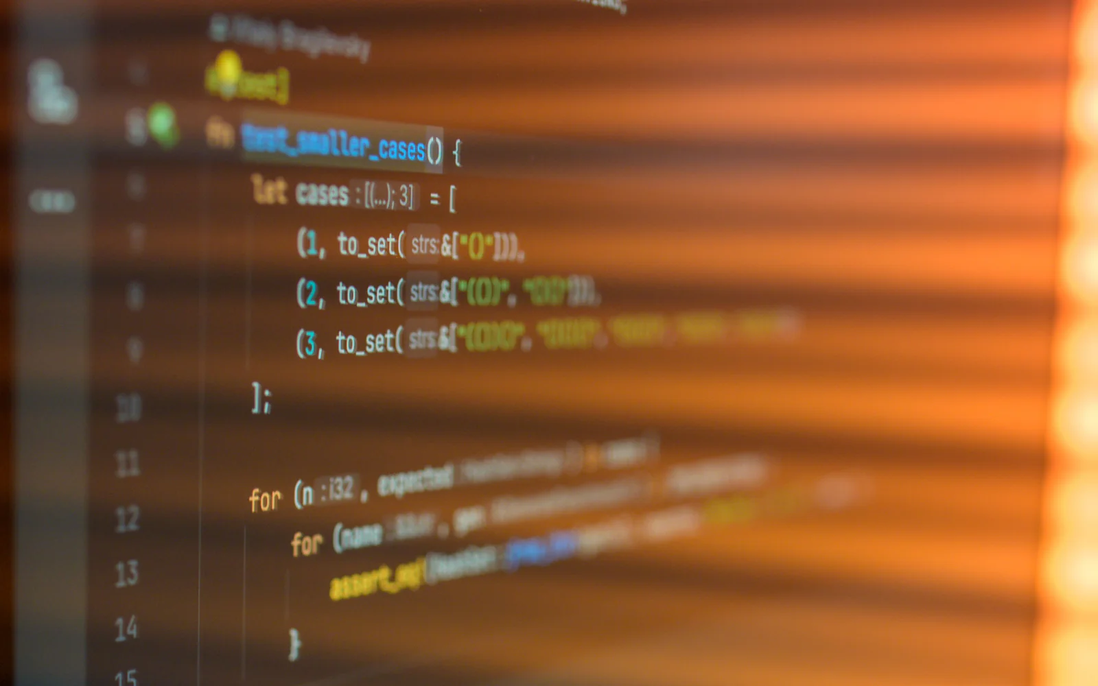 Colorful programming code on a dark monitor with warm reflections.